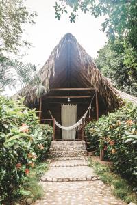 a building with a thatched roof with a pathway leading to it at Cabaña Wiwa Tayrona in Santa Marta