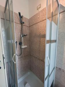 y baño con ducha y puerta de cristal. en Affittacamere I Gigli di Mare, en Marina di Bibbona