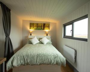 Ce lit se trouve dans une petite chambre dotée d'une fenêtre. dans l'établissement Holly Lodge - Quirky Shepherd's Hut With Hot Tub - Bespoke Made From A Salvaged Railway Carriage, à Boston