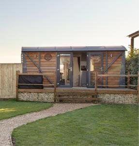 a modular home with a fence and grass at Holly Lodge - Quirky Shepherd's Hut With Hot Tub - Bespoke Made From A Salvaged Railway Carriage in Boston