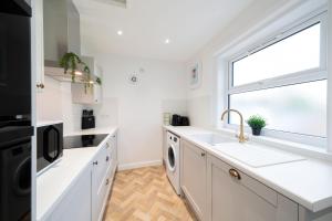 a kitchen with white cabinets and a sink and a window at Clubhouse Cottage on Eden View Estate in St Andrews
