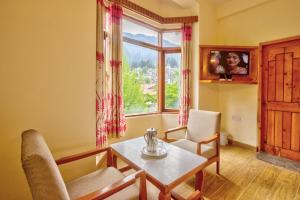 HOTEL ROYAL Manali في مانالي: غرفة معيشة مع طاولة وكراسي ونافذة