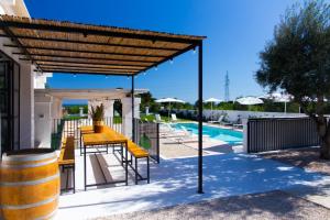 pérgola de madera con mesa amarilla y sillas junto a la piscina en Tenuta Amostuni-Country House, en Ostuni