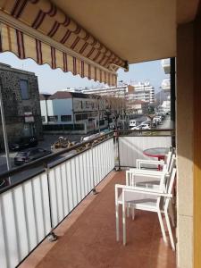 a balcony with two white chairs and a view of a city at Amplio y soleado Alquilo apartamento entero de 3 hab 5 pax in Zarautz