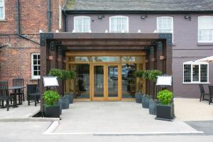 uma entrada para um edifício com vasos de plantas em The Farmhouse em Derby