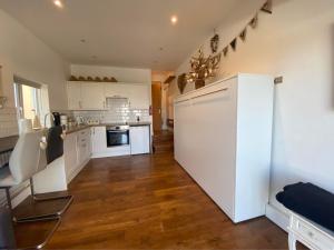 a kitchen with white cabinets and a white refrigerator at Ty Cerrig seaside Annexe, New Quay in New Quay