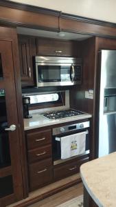 a kitchen with a stove and a microwave at Hill Country Luxury RV Glamp: Twin Falls, Texas in Boerne
