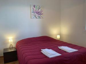 een slaapkamer met een rood bed en 2 handdoeken erop bij Punta di mare, appartements bord de mer in Linguizzetta
