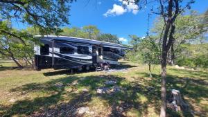 una caravana estacionada en un campo en el bosque en Hill Country Luxury RV Glamp: Twin Falls, Texas en Boerne