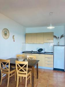 een keuken met een tafel en stoelen en een koelkast bij Punta di mare, appartements bord de mer in Linguizzetta