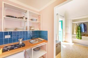 uma cozinha com um lavatório e uma parede de azulejos azuis em Olivieri 25 - Gioia Apartments em Procida