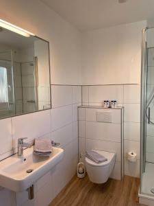 ein Badezimmer mit einem Waschbecken, einem WC und einem Spiegel in der Unterkunft Wohnung Peper in Juist