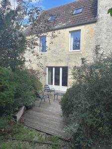 ein Haus mit zwei Stühlen auf einer Holzterrasse in der Unterkunft LE SEIZE - Gîte 4 personnes - entre Caen et la mer in Cairon