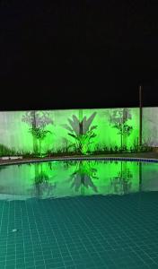 PIRANHAS HOTEL في ببرانا: مسبح مع لوحة خضراء على جانب المبنى