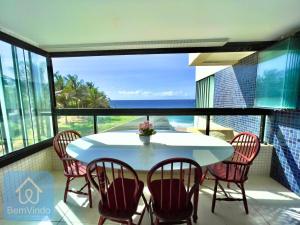 una mesa y sillas en un balcón con vistas al océano en Apartamento completo e pé na areia no Rio Vermelho, en Salvador