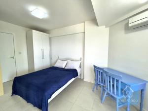 1 dormitorio con cama azul y banco azul en Apartamento completo e pé na areia no Rio Vermelho, en Salvador