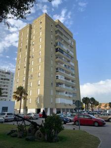 um grande edifício com carros estacionados num parque de estacionamento em Azvalia - Valdelagrana Mirador de la Bahía, Playa, piscina, parking, vistas ! em El Puerto de Santa Maria
