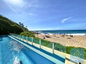 una piscina con una playa de fondo en Apartamento completo e pé na areia no Rio Vermelho, en Salvador