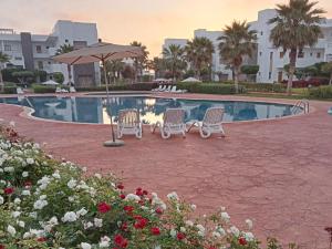 two chairs and an umbrella next to a swimming pool at Perla Saidia Appartement in Saïdia