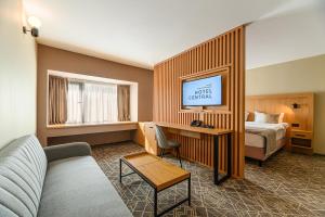 a hotel room with a bed and a couch and a desk at HOTEL CENTRAL in Paşcani