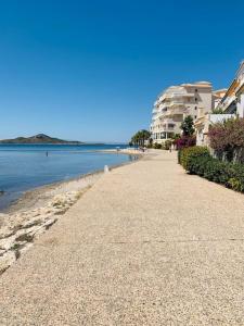 a beach with a building and the ocean on a clear day at Cabo Romano, 3 Bedroom,2 Bathroom Apartment with Sea Views LMHA 14 in La Manga del Mar Menor