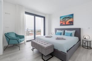 a bedroom with a large bed and a blue chair at Dream Villa with ocean view in Lourinhã