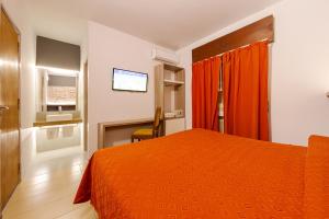 1 dormitorio con 1 cama de color naranja y TV en Hotel El Condado en Villa Carlos Paz