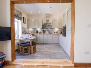 a kitchen with white cabinets and a table at 3 Rhyd Drive in Colwyn Bay +19 photos