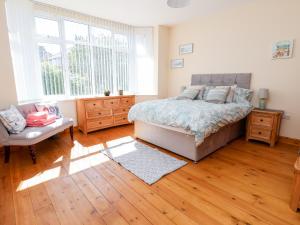 sypialnia z łóżkiem oraz drewnianą podłogą i oknami w obiekcie 3 Rhyd Drive w mieście Colwyn Bay