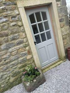 uma porta de um edifício de pedra com um vaso de planta em Tosside Fold Farm Cottage em Skipton