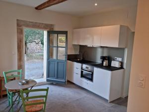 a kitchen with white cabinets and a table and a door at Gîtes de l'Estagnol in Villeneuve-lès-Maguelonne