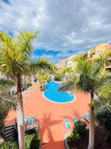 un complejo con una piscina con palmeras y sillas en Laderas del Palmar Luxury, en Palm-mar