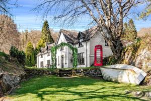 une maison blanche avec un bateau devant elle dans l'établissement Taychreggan Hotel, à Kilchrenan