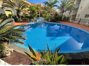 una gran piscina azul con palmeras y un edificio en Laderas del Palmar Luxury, en Palm-mar