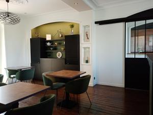 une salle à manger avec deux tables et des chaises vertes dans l'établissement Hôtel de France, à Pléneuf-Val-André