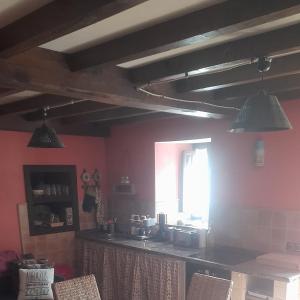 Una cocina con paredes rosas y vigas de madera. en Casa Capricho, en Proaza