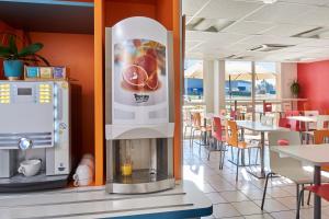 a drink dispenser in a restaurant with tables and chairs at Kyriad Direct Mont De Marsan - St Avit in Saint-Avit