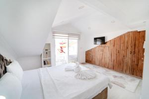 a white bedroom with a large bed with a wooden wall at Flat with Mountain View in Fethiye in Fethiye