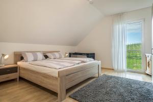 een slaapkamer met een groot bed en een groot raam bij Haus Barbara, Ferienwohnung, 90qm in Unterreitnau