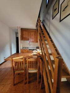 uma cozinha com uma mesa e cadeiras de madeira e uma escadaria em La casa lassù em Tarvisio