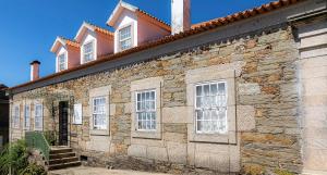 een oud stenen gebouw met witte ramen bij Casa do Hospital-Guest House in Abaças