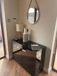 a dresser with a lamp and a mirror in a room at Prancing Horse Cottage in Sabden
