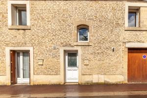 ceglany budynek z białymi drzwiami i oknami w obiekcie La Grange - Charmante maison à Langrune-sur-mer w mieście Langrune-sur-Mer