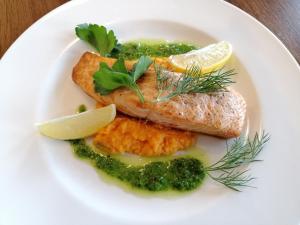 un plato blanco de comida con pescado y verduras en Restauracja Teo, en Cieszków
