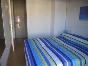 1 dormitorio con 1 cama con una manta a rayas de colores en Almare 38, en Grado