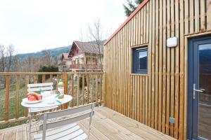 a wooden deck with a table and chairs on a house at POP'S colors - Chalet dans les Vosges in Ventron