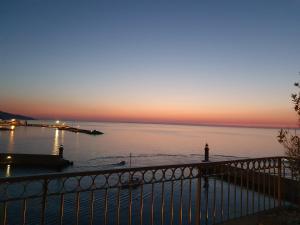 a sunset over a body of water with a lighthouse at Hôtel Des Gouverneurs in Bastia