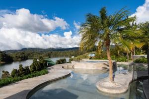 a swimming pool with a palm tree next to a river at Tau House in Guatapé