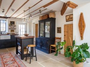 Little Oakley Cottage في Sandford Saint Martin: مطبخ مع دواليب زرقاء وطاولة وكراسي
