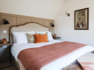 a bedroom with a large white bed with orange pillows at Little Oakley Cottage in Sandford Saint Martin